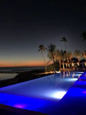 Twilight shot of Flamingo Pool Villa with illuminated pool reflecting deep blue skies.
