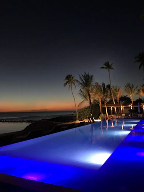 Twilight shot of Flamingo Pool Villa with illuminated pool reflecting deep blue skies.