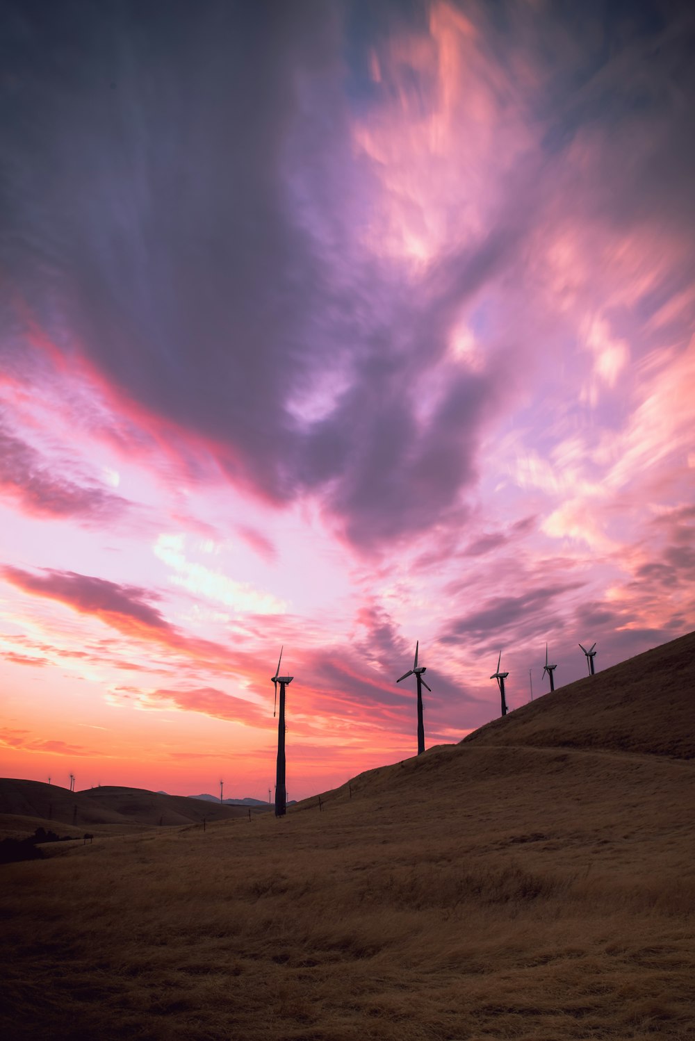 wind mills on hill under cloudy sky