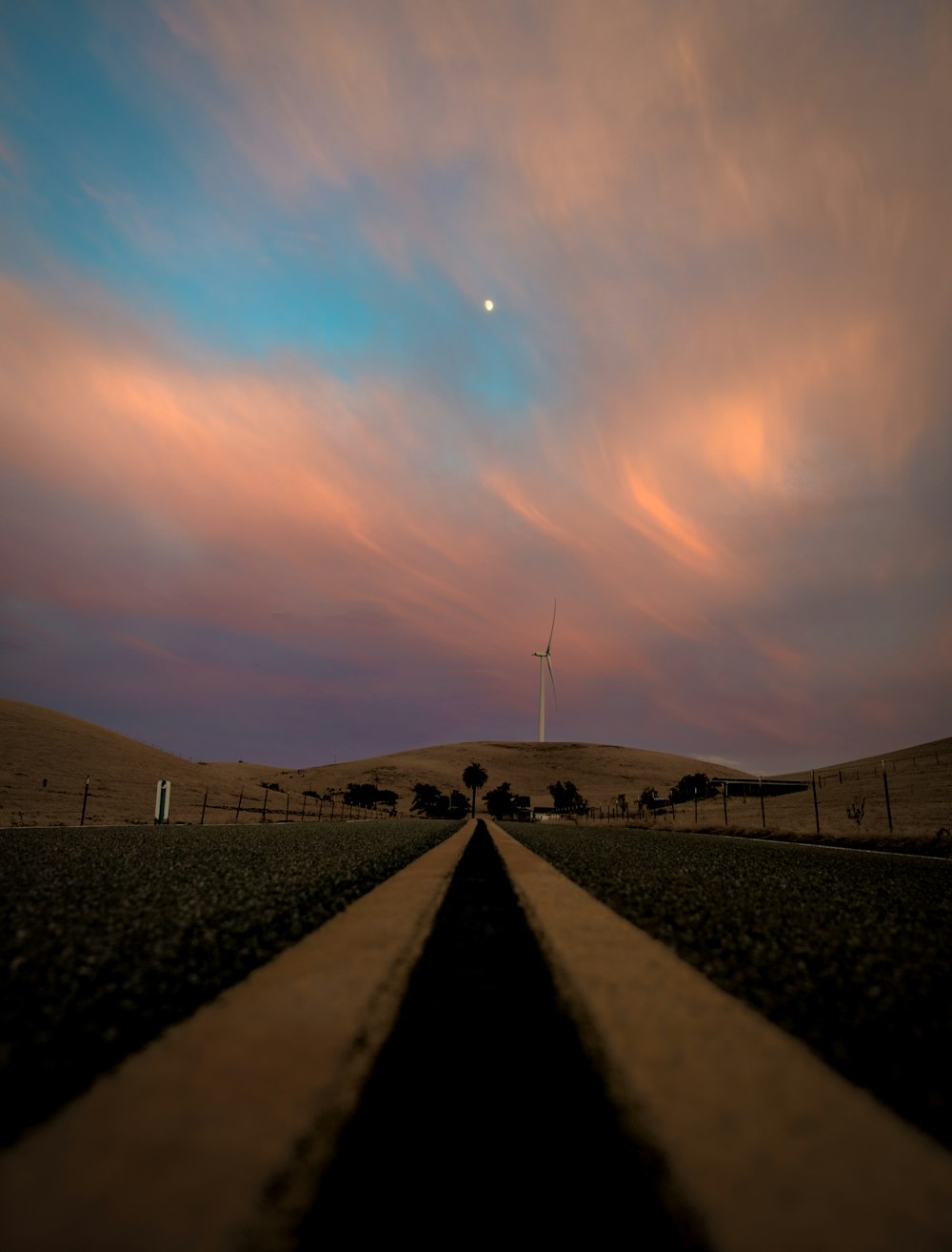 gray and white dirt road under blue and white clouds