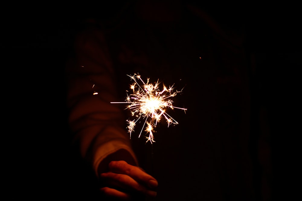 person holding lighted sprinklers