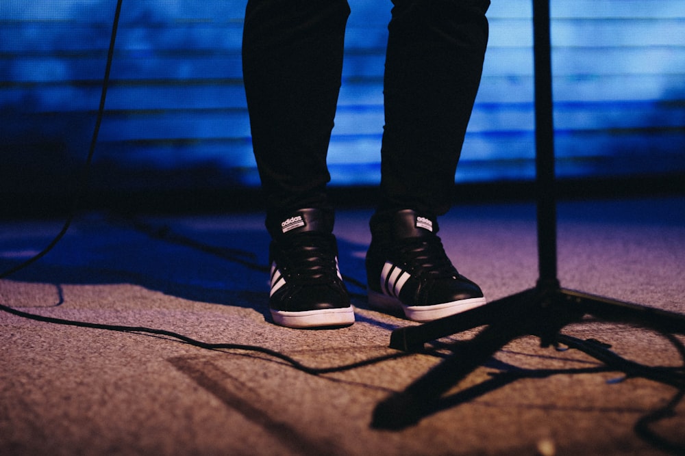 person showing pair of black-and-white adidas shoes