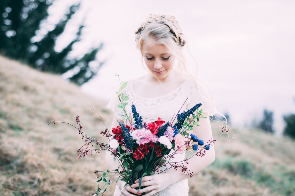 girl holding assorted bouquet flowers while looking down