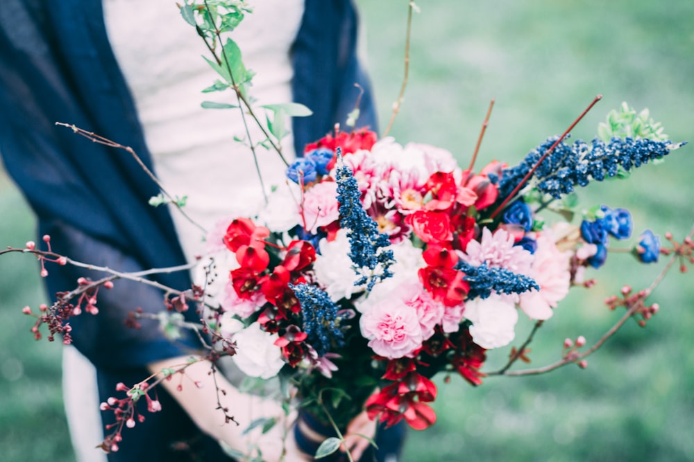 person holding bouquet of pink, red, and blue petaled flowers