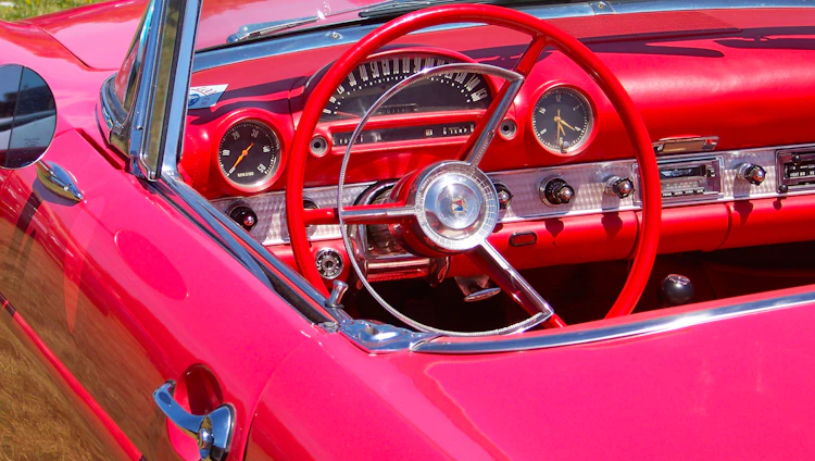 A cozy car interior with a sleek dashboard featuring a newly installed car radio glowing softly against deep crimson upholstery.