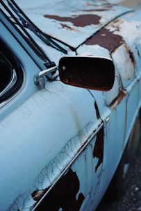 A friendly technician inspecting a rusty old car ready for cash offer.