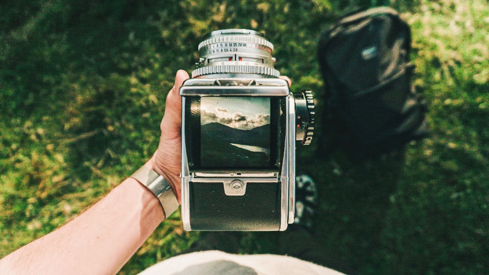 person holding black and gray folding camera