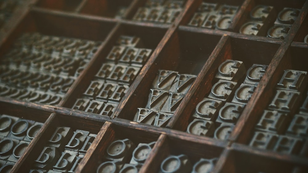 gray assorted-letter jewelries in brown wooden organizer boxes