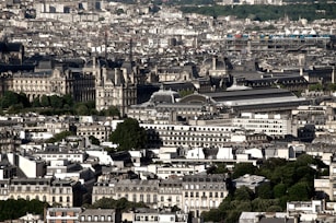 A bustling cityscape featuring a dense arrangement of historic buildings and modern structures. Prominent landmarks with intricate architectural details are surrounded by lush greenery and busy streets.