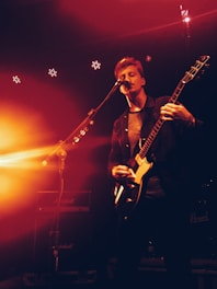 A soulful musician performing on stage with a guitar, surrounded by warm lighting.