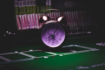 silver twin bell alarm clock on green table