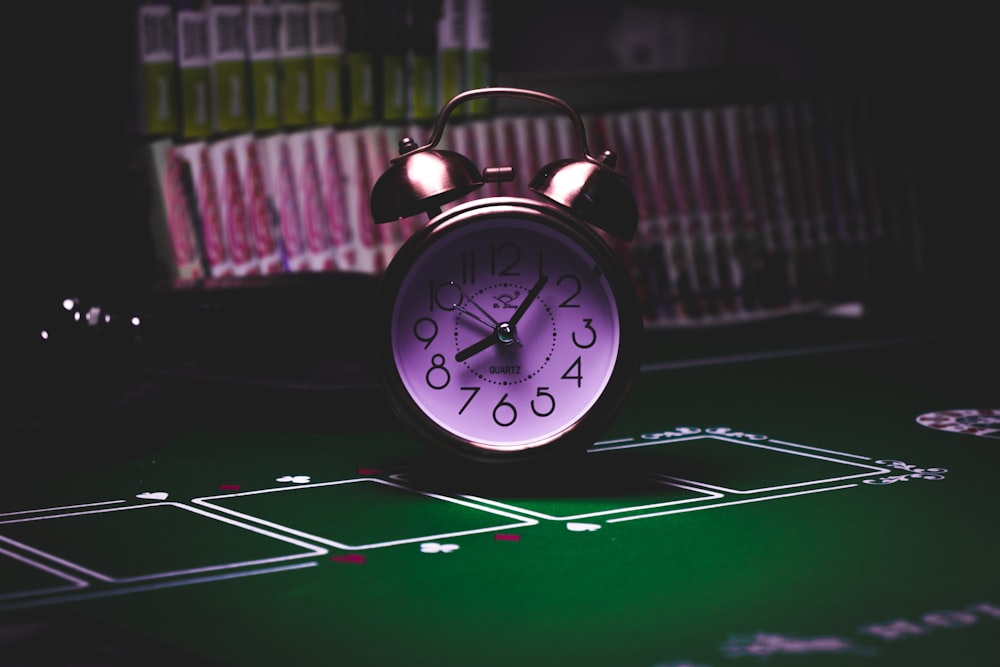 silver twin bell alarm clock on green table