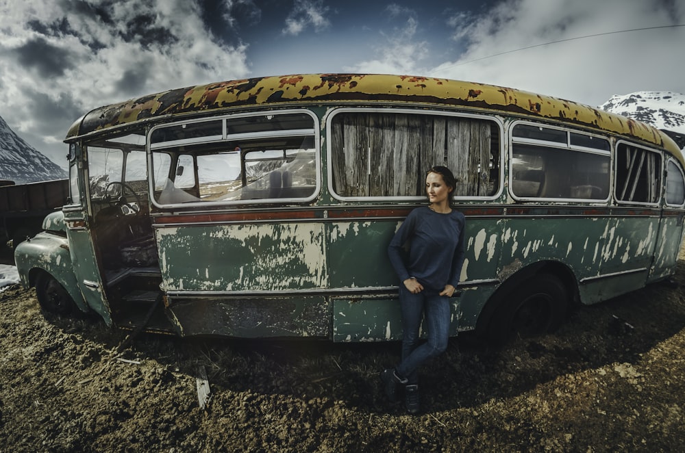 woman leaning on green bus under blue sky