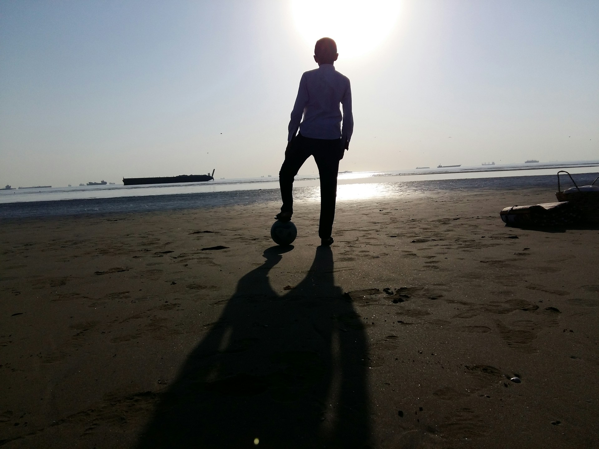 Close-up of a player skillfully controlling the ball on the sand, with the vibrant Napoli coastline in the background.