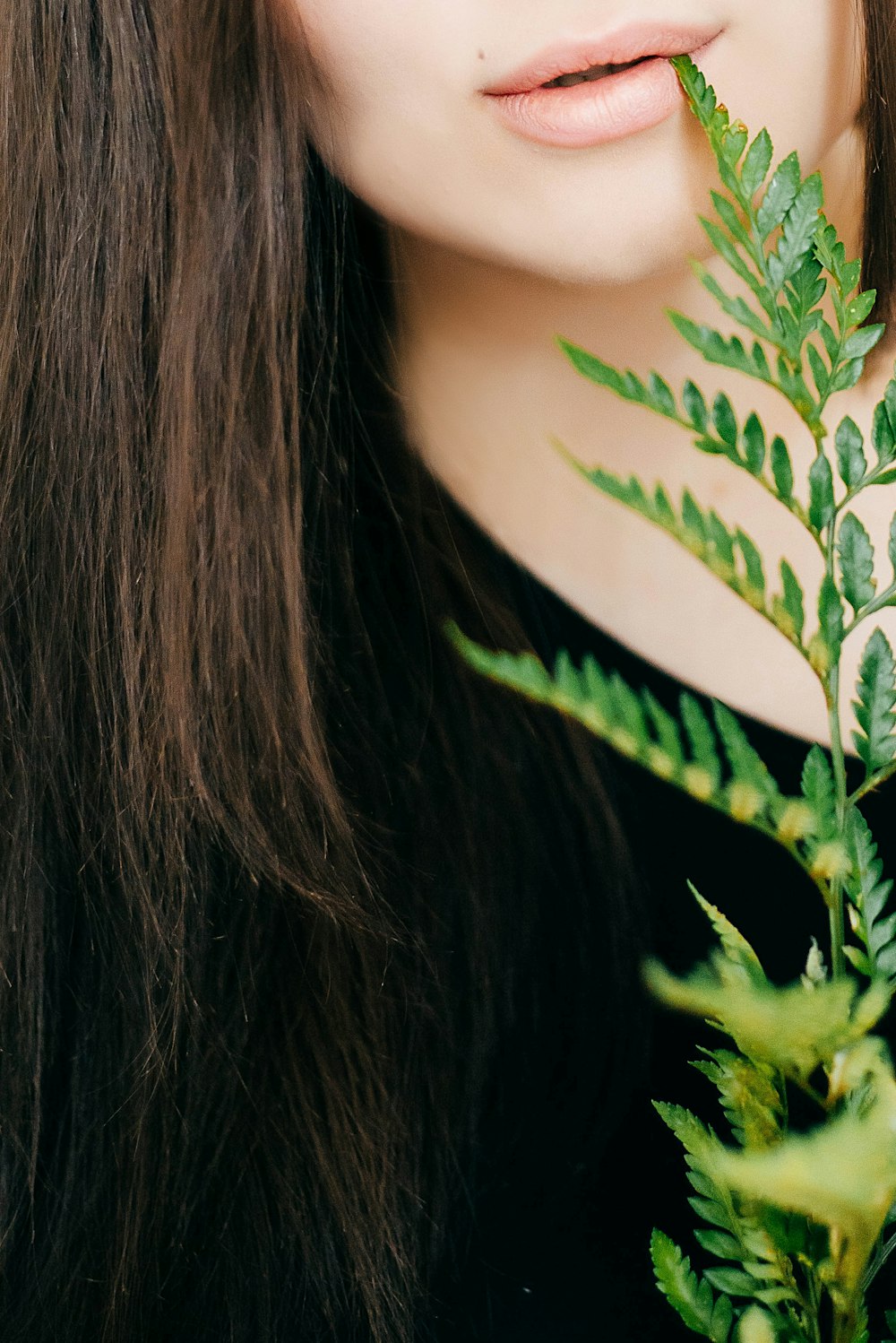 黒いトップと緑の葉の植物を身に着けている女性のクローズアップ写真