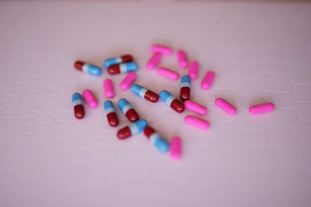 Close-up of aura's three color-coded pills—blue, pink, and obsidian—arranged elegantly on a sleek white surface.
