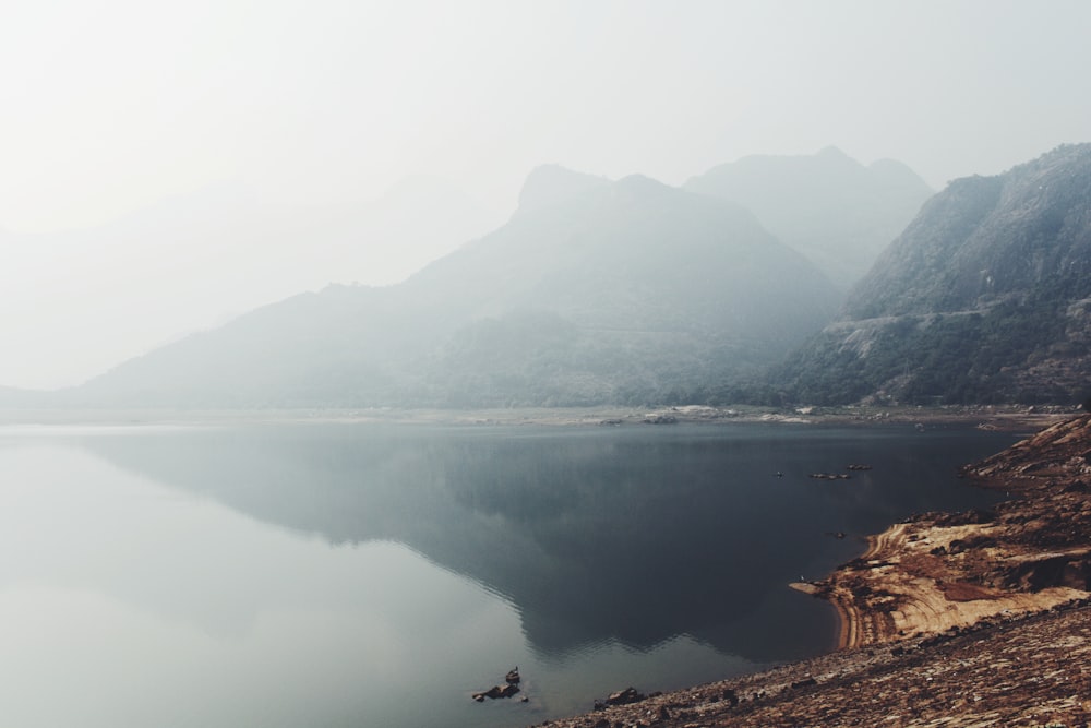 mirror photography of mountain under white clouds