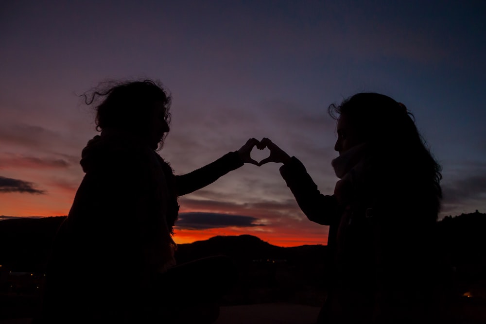 silhouette of persons doing heart hand