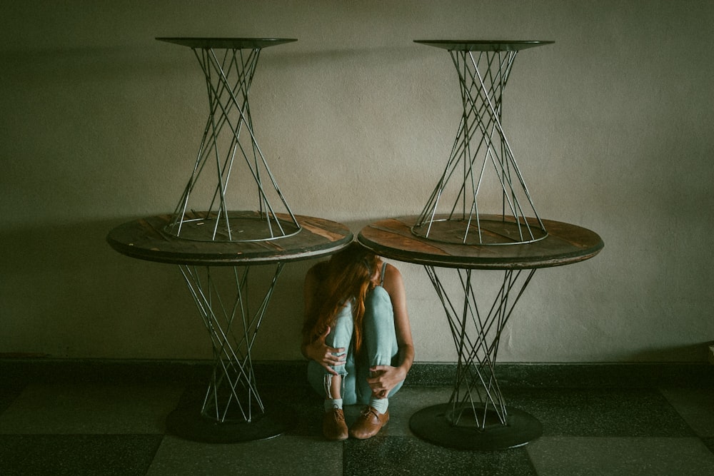 woman between and under round brown wooden pedestal dining tables