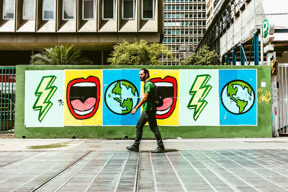 man walking on street near graffiti wall during daytime