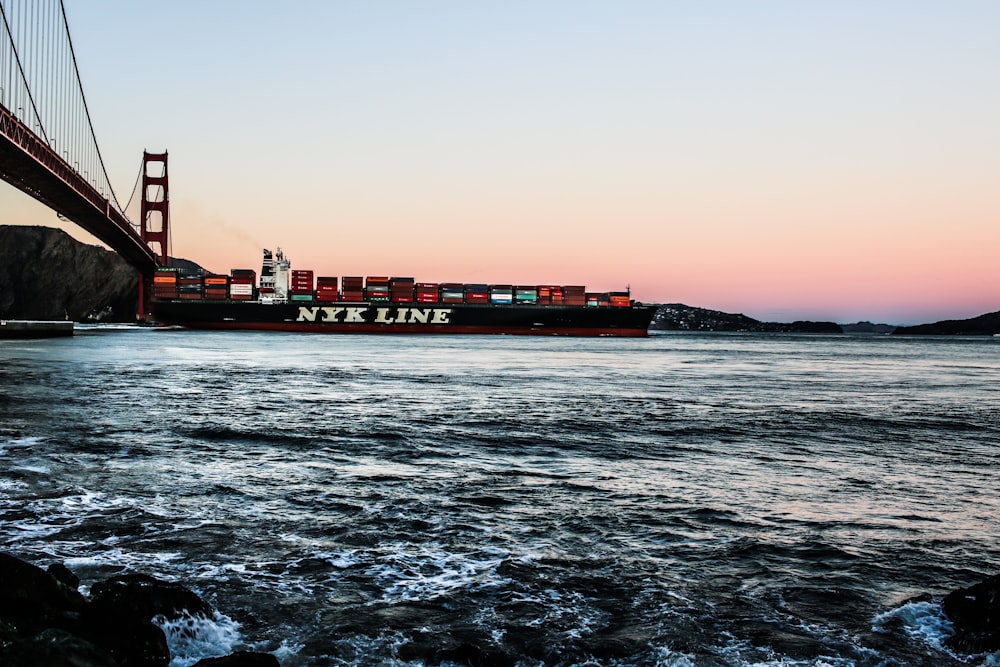 black shipping ship crossing Golden Gate bridge