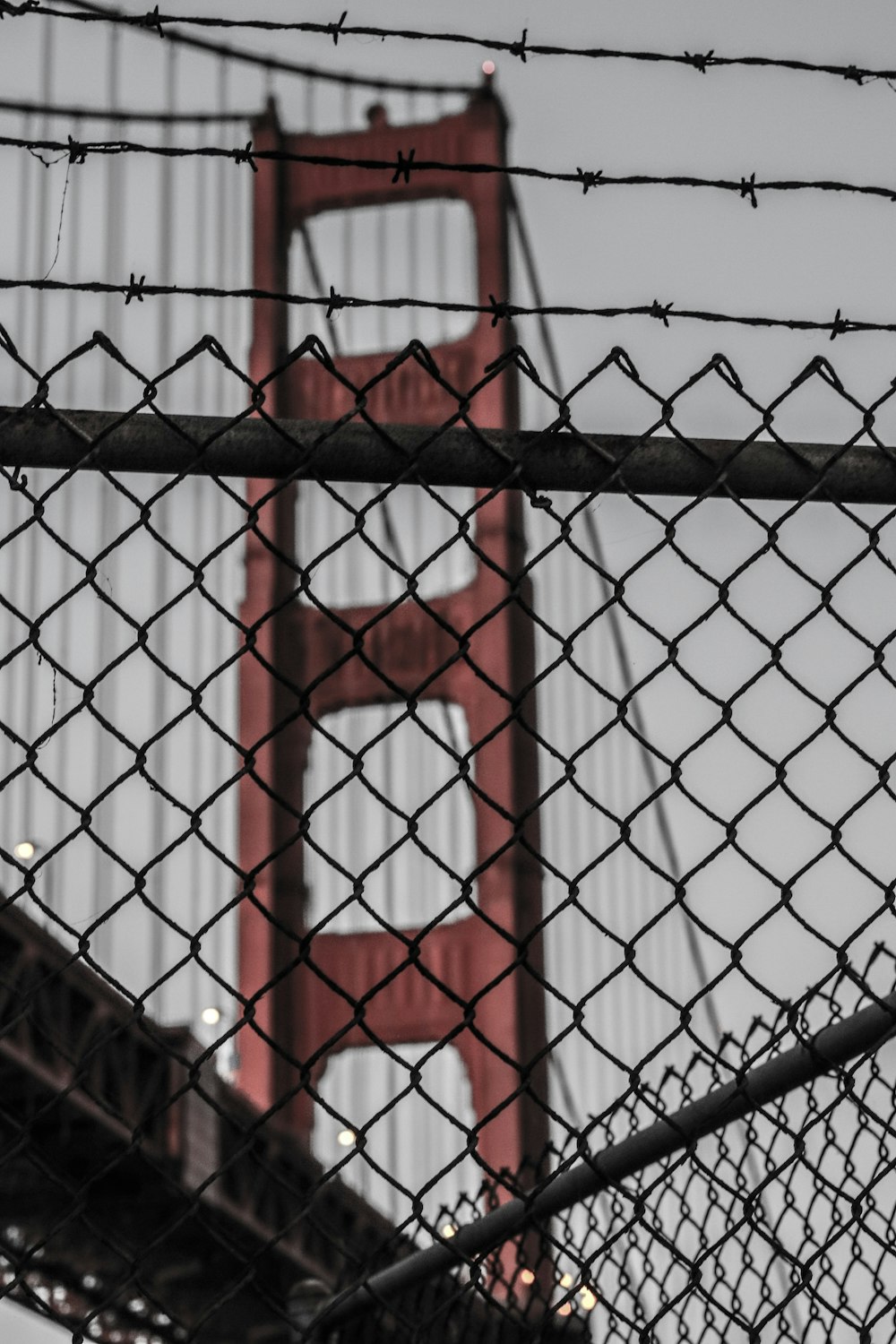 photo of diamond link fence near red bridge at daytime