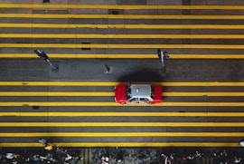 Illustration of a yellow car with passengers and drivers linked by blue route lines.