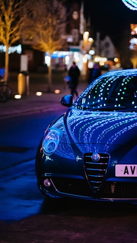 A sleek, modern car wrapped in vibrant film, parked against the dynamic cityscape of Shenzhen at dusk.
