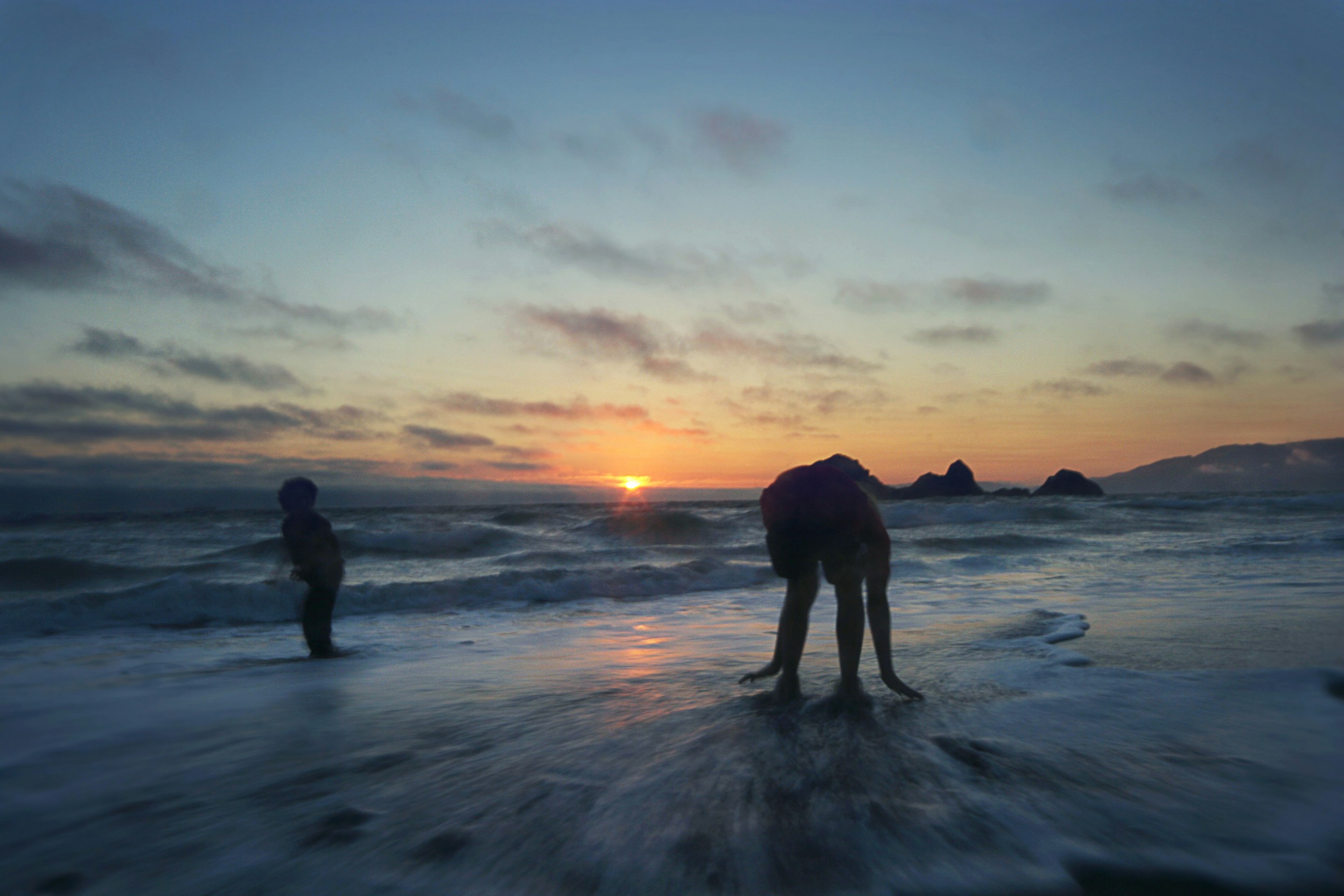two people standing on ocean during sunset