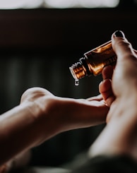 person holding amber glass bottle