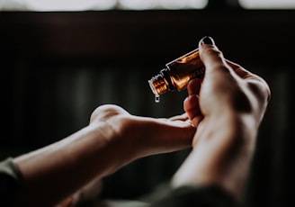 person holding amber glass bottle