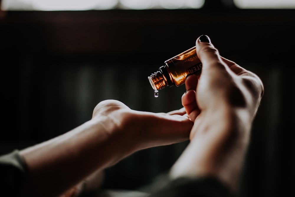 person holding amber glass bottle