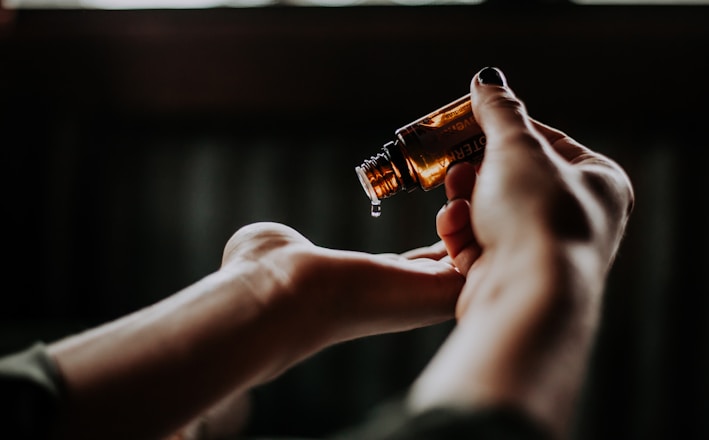 person holding amber glass bottle