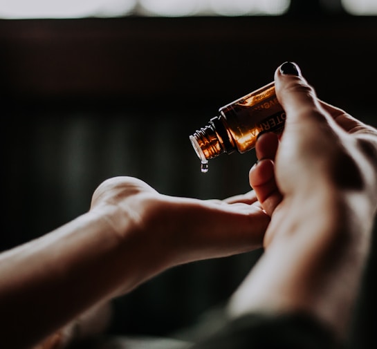 person holding amber glass bottle