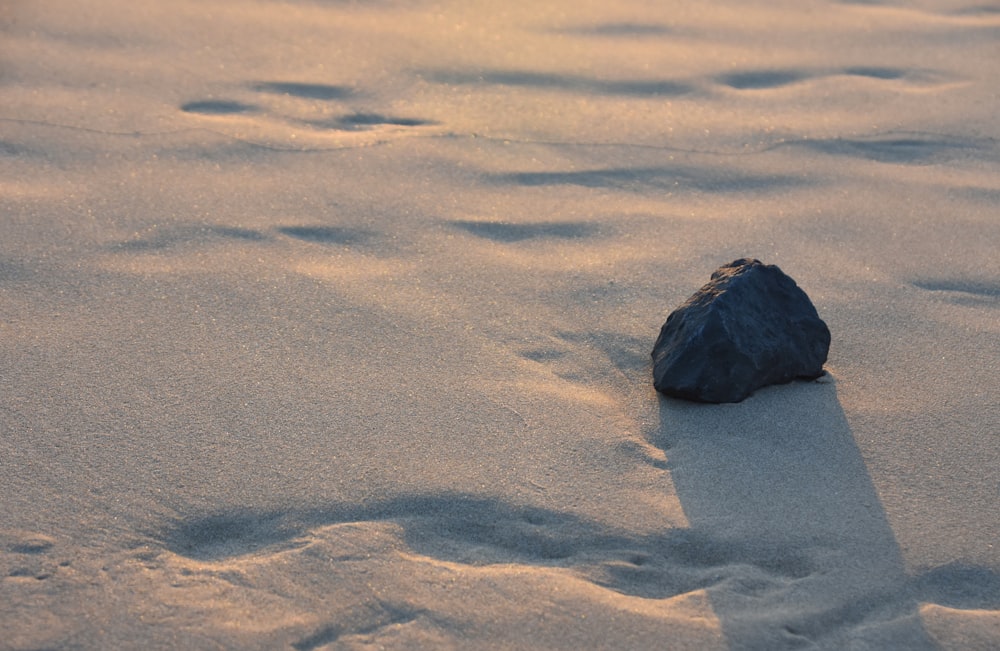 schwarzes Steinfragment auf weißem Sand