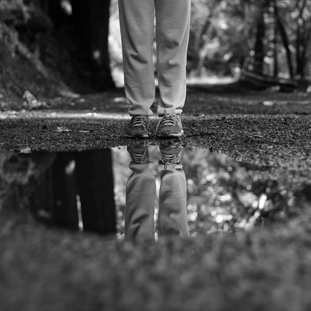 grayscale photography of person standing between trees