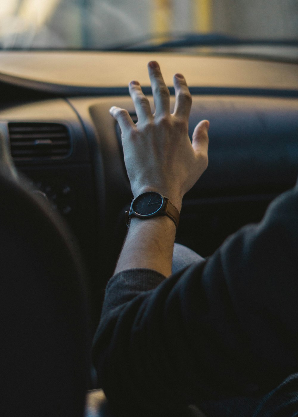 uma pessoa segurando a mão para fora da janela de um carro