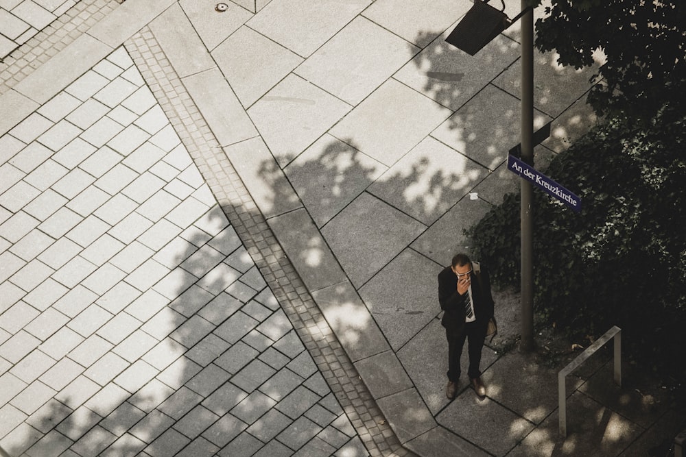 man wearing suit standing near gray post during daytime