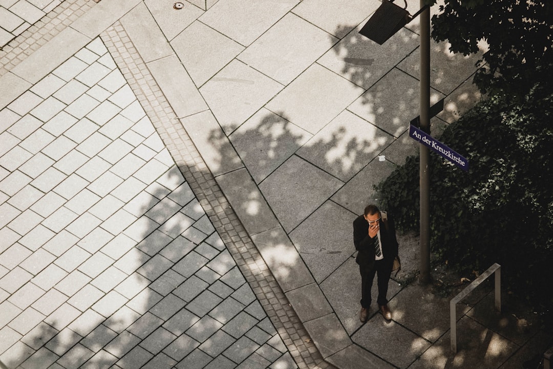 man wearing suit standing near gray post during daytime