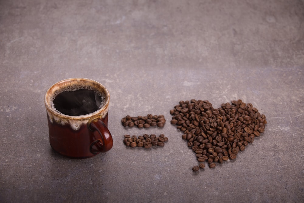 grain de café à côté de la tasse en céramique brune