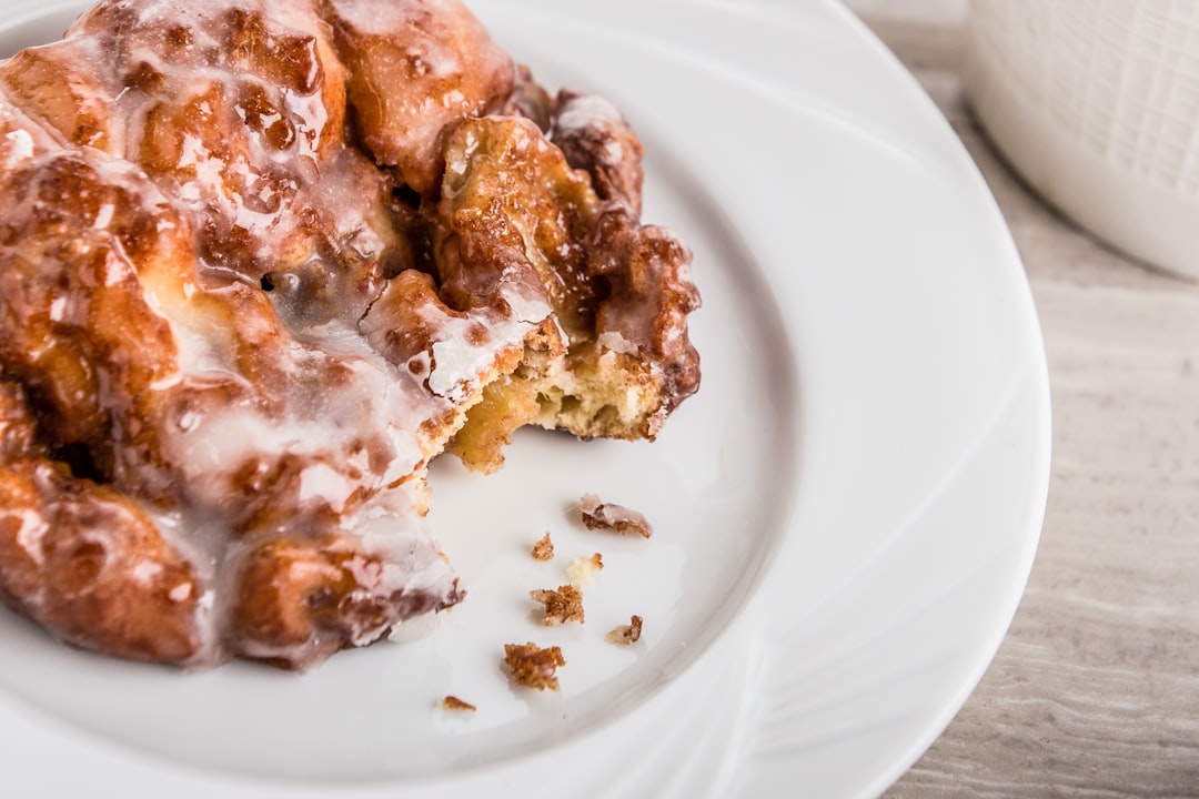 Apple fritter with bite missing on a white plate