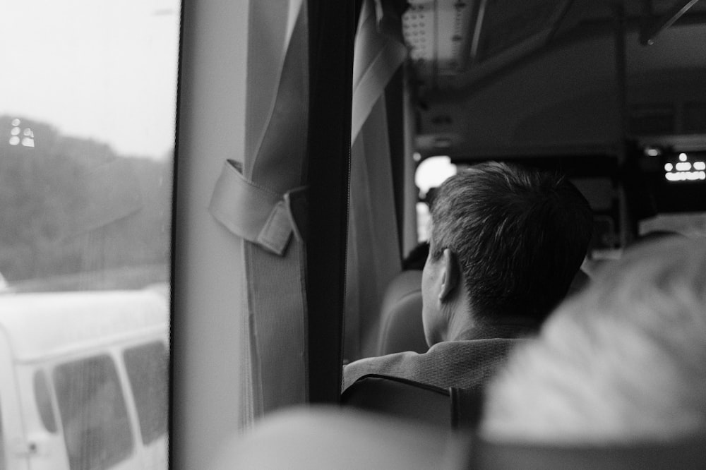 grayscale photography of man sitting on chair inside vehicle