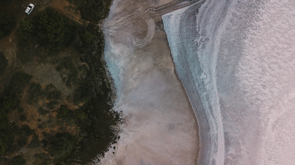 aerial photography of white vehicle running on rough road near shore