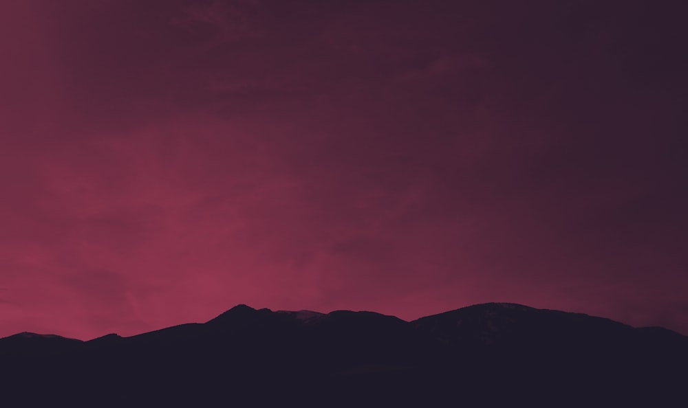 silhouette of mountain under red sky