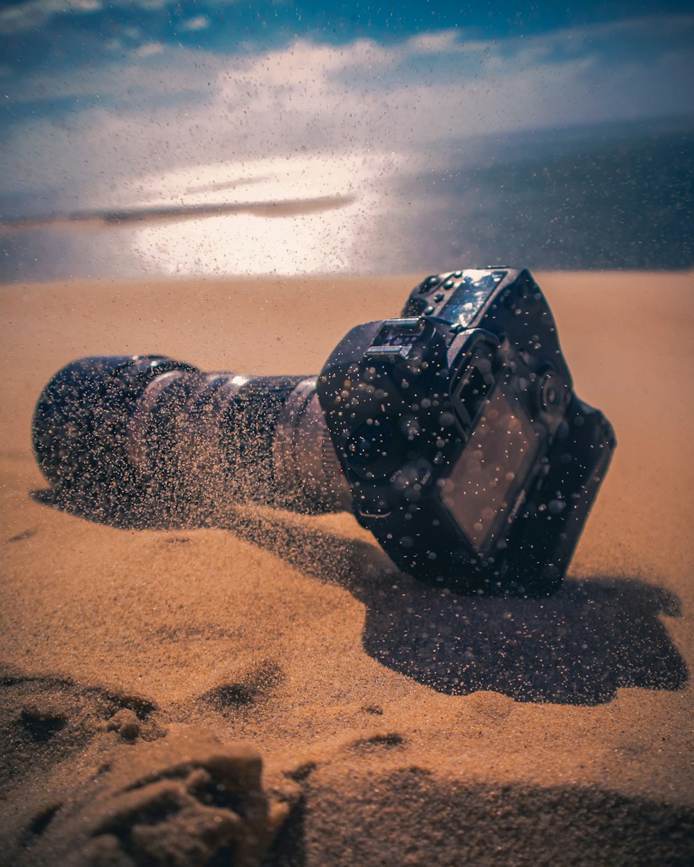 砂の上の黒いデジタル一眼レフカメラ