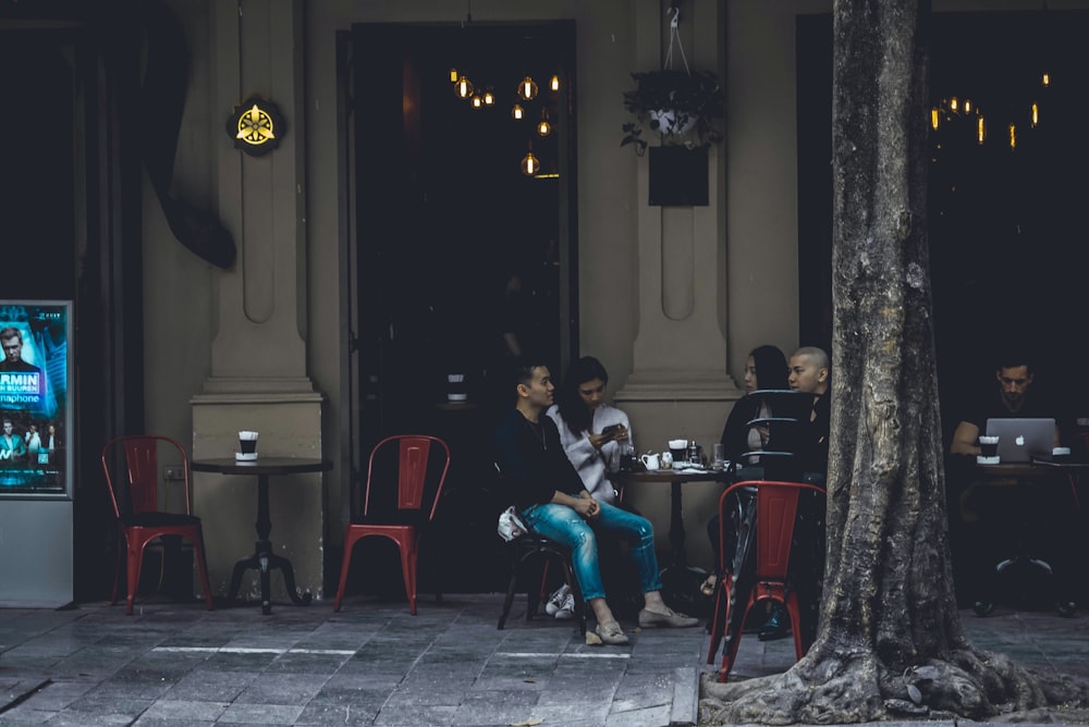 group of people sitting on chair with table in front of building