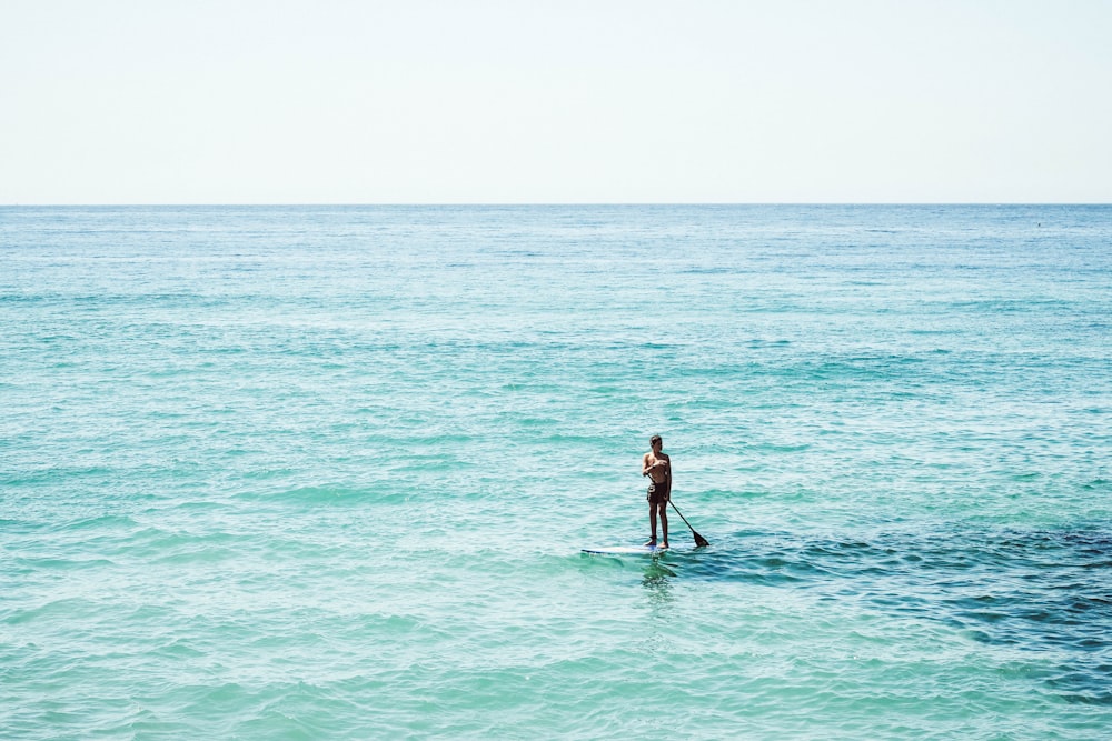 man on surfboard under white sky