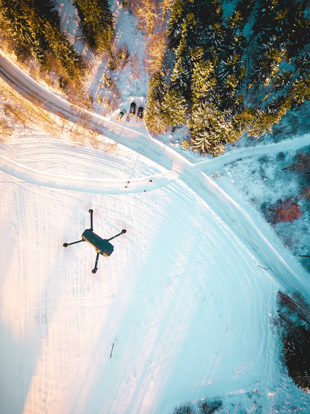 black quadcopter drone flying over snow field during daytime