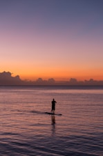 man paddleboarding during sunset