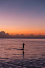 man paddleboarding during sunset
